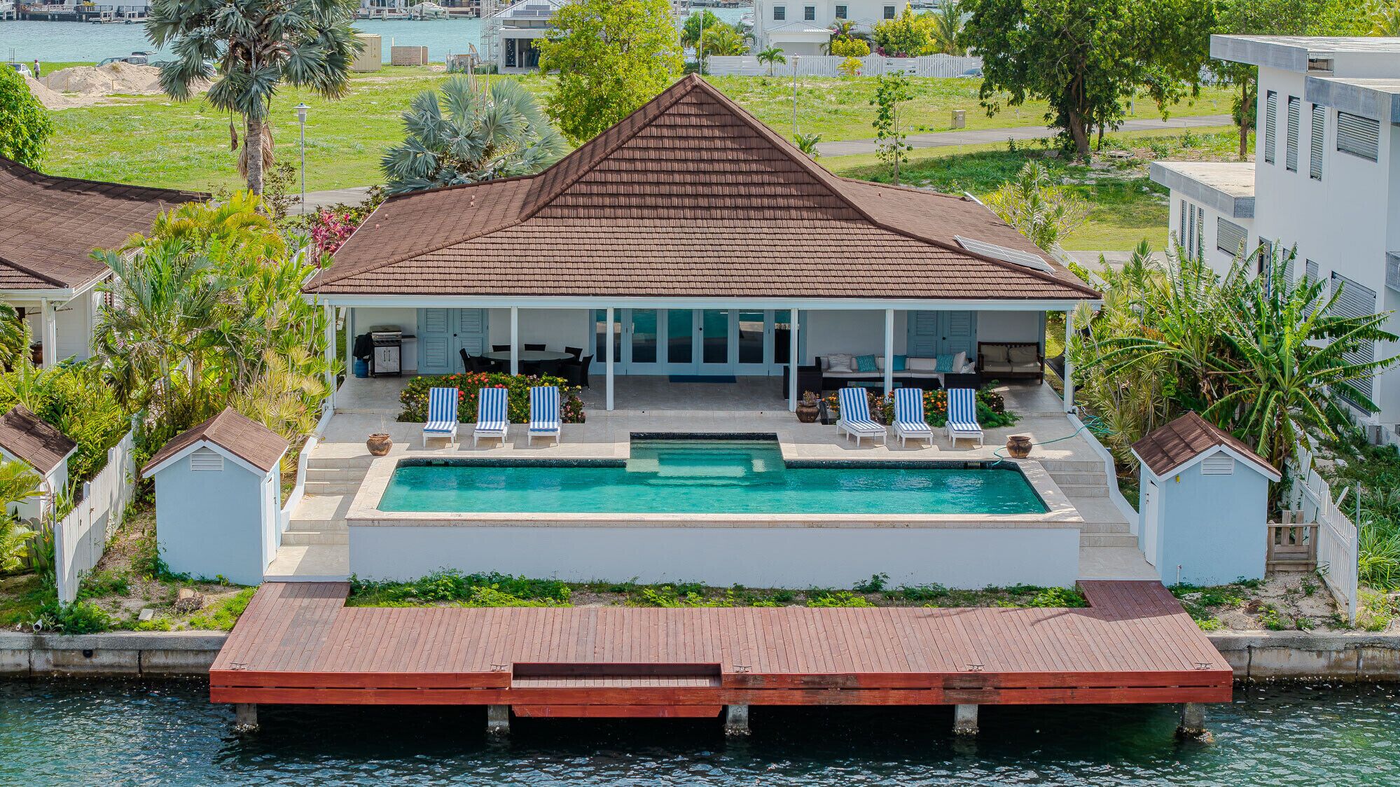 Une maison avec une piscine, un patio couvert et une jetée qui s’avance dans l’eau.