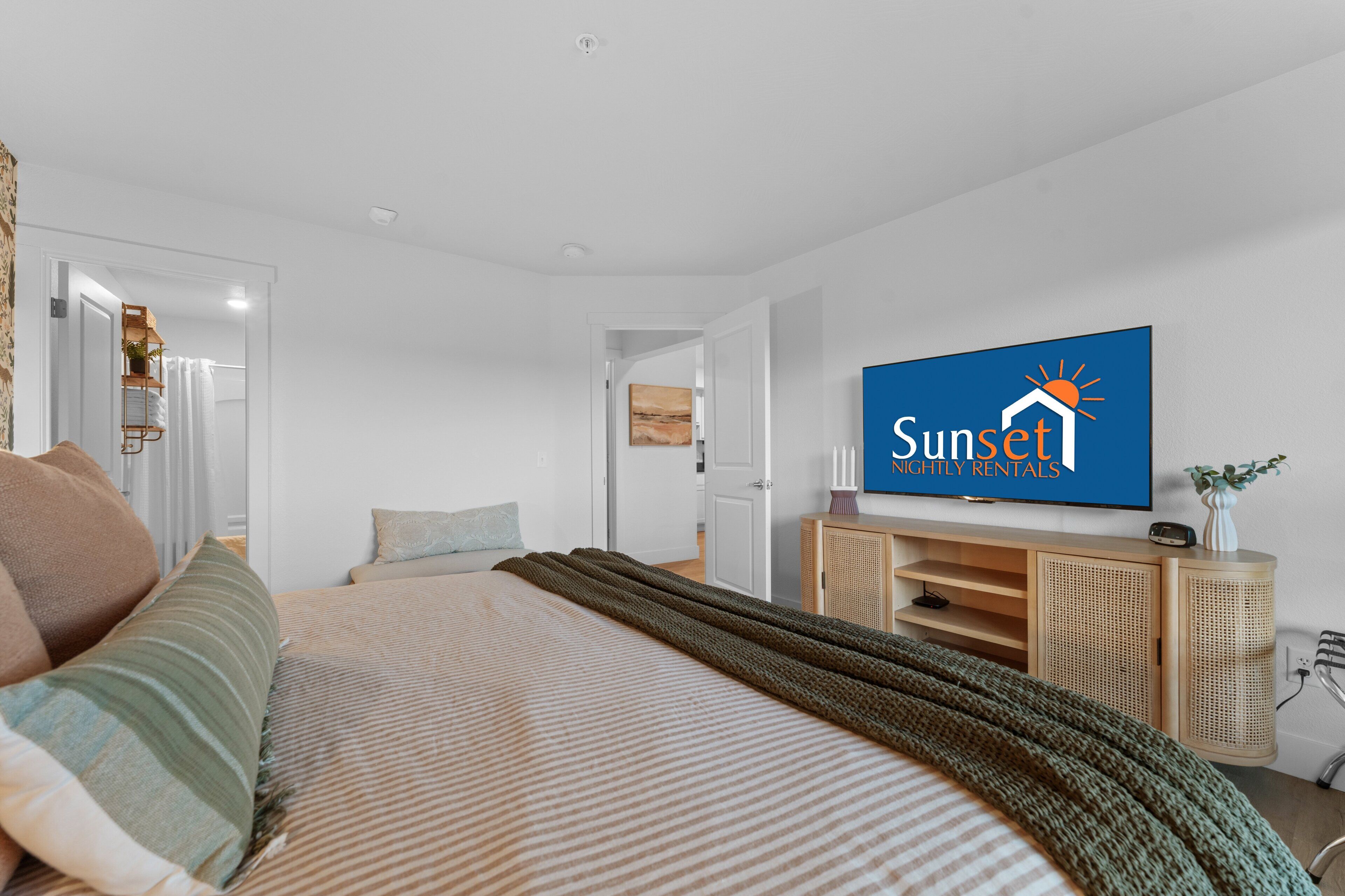 A modern bedroom with a bed, a television, a wooden cabinet, and a door leading to another room.