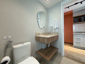 Een moderne badkamer met toilet, wastafel en spiegel.