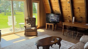 A cozy room with a wooden ceiling, a television, a sofa, and a chair.