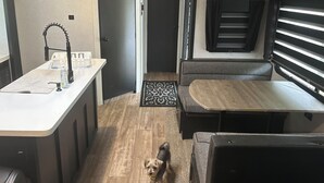 En kompakt autocamper indretning med et tekøkken, spiseplads og soveområde.