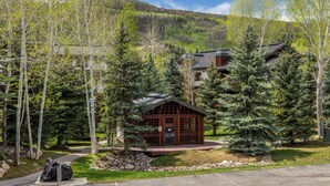 A lodge with a wooden exterior, surrounded by trees and a mountain backdrop. - Mountain Comfort Between Downtown and the Slopes – Pines at Ore House 201! (Steamboat Springs)