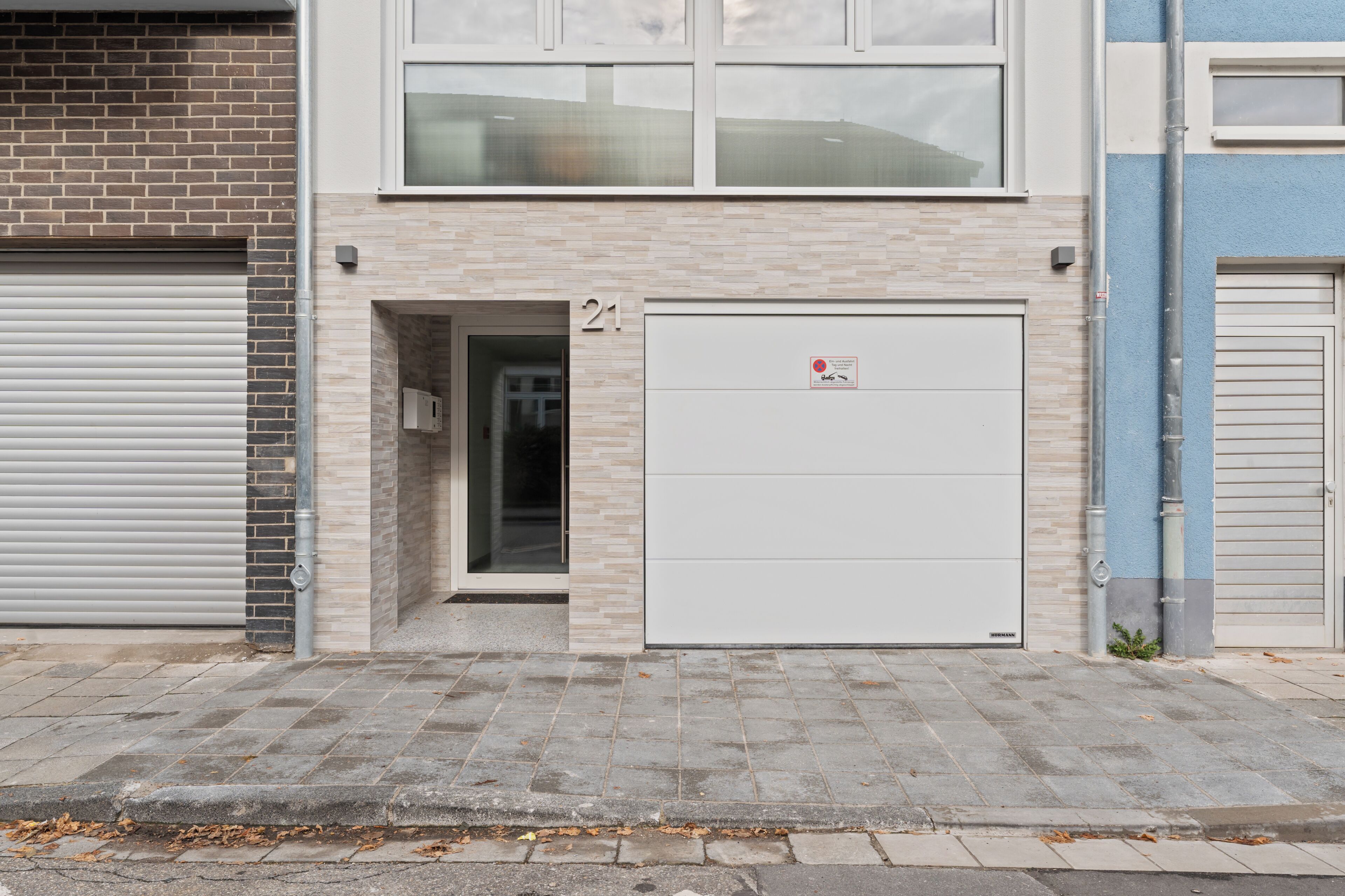 A building with a closed garage door, a number '21' sign, and a small entrance.