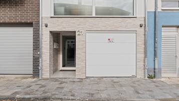 A building with a closed garage door, a number '21' sign, and a small entrance.