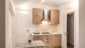 A compact kitchen with a sink, stove, and cabinets, a small dining table with chairs, and a door leading to another room. - Canterno Country House - near Fiuggi (Trivigliano)