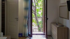 A room with a bed, a dresser, a mirror, and a balcony with a view of trees. - Canterno Country House - near Fiuggi (Trivigliano)