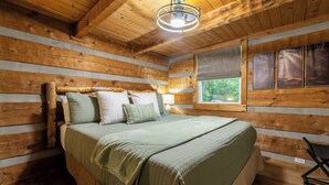 A wooden cabin bedroom with a bed, pillows, a window, and a ceiling light. - Visit Dollywood! 2 King Beds! Cedar Brooke Haven (Sevierville)
