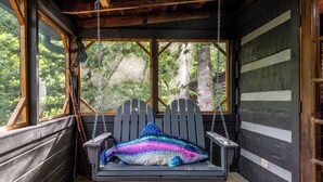 A wooden cabin with a swing seat and a view of the forest. - Visit Dollywood! 2 King Beds! Cedar Brooke Haven (Sevierville)