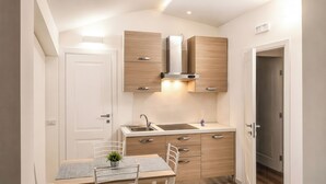 Een moderne keuken met een ingebouwde kookplaat, een spoelbak en een eethoek met een tafel en stoelen.