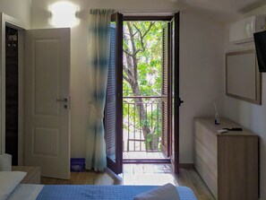 A bedroom with a bed, a dresser, a nightstand, and a window with a view of trees. - Canterno Country House - nei dintorni di Fiuggi (Lazio)