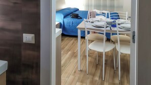 Een moderne kamer met een eethoek, een blauwe bank en een raam met gordijnen.