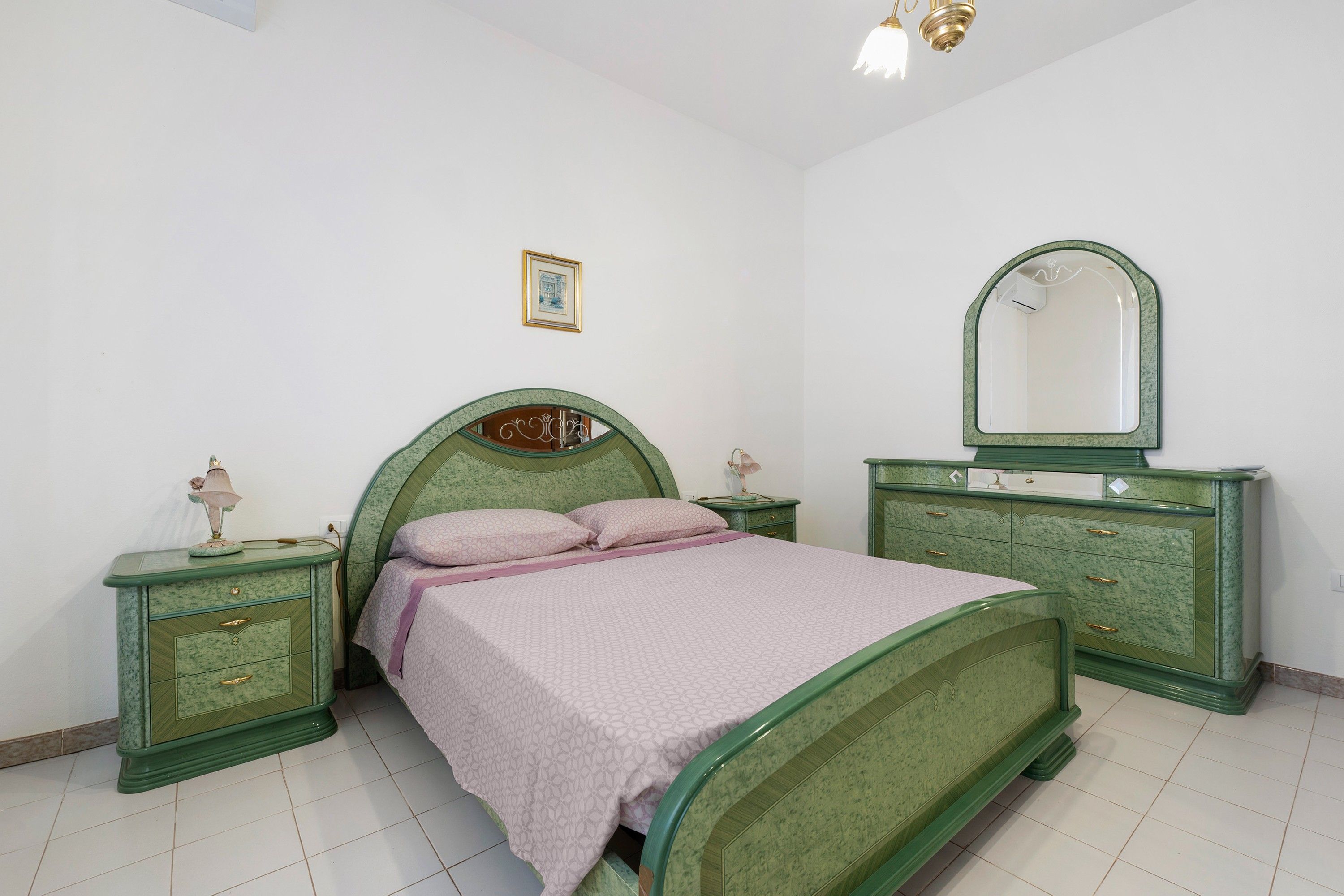 Une chambre à coucher avec un lit, des tables de chevet, une commode, un miroir et un tableau accroché au mur.