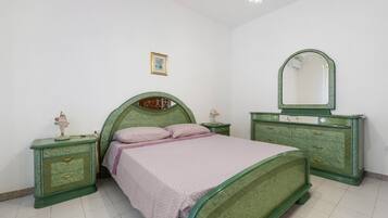 Une chambre à coucher avec un lit, des tables de chevet, une commode, un miroir et un tableau accroché au mur.