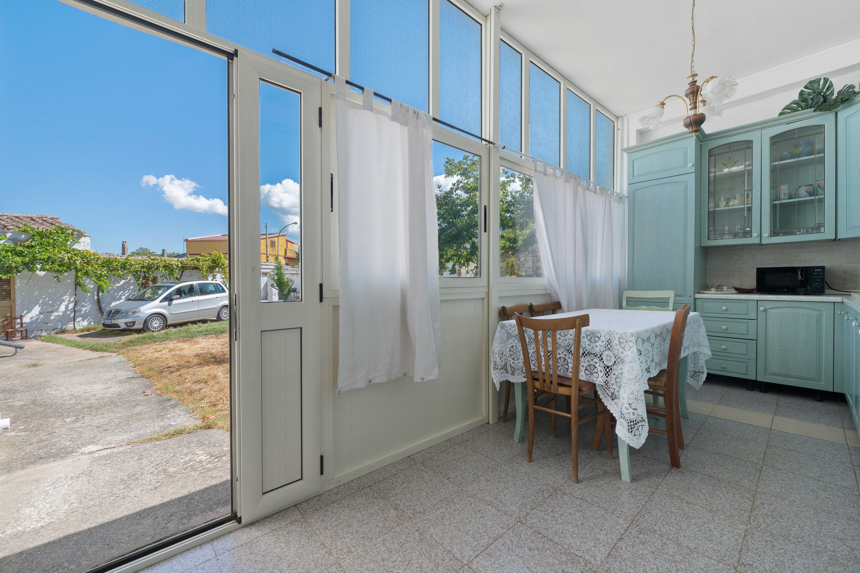 A room with a dining table, chairs, a kitchen area with cabinets, and a sliding glass door leading to an outdoor area.