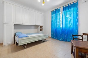 Un dormitorio con cama, escritorio y armario.