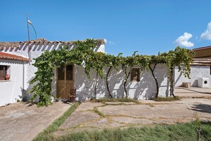 Un bâtiment blanc avec un toit en tuiles, une porte en bois et une fenêtre avec des volets.