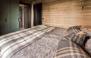 A bedroom with a wooden headboard, a bed with patterned bedding, and a green door. - Stunning home in Sjusjøen with sauna (Sjusjøen)