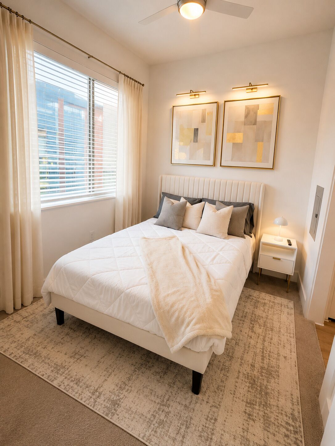 Une chambre à coucher comprenant un lit, des tables de chevet, un ventilateur de plafond et deux appliques murales.
