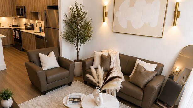 Ein modernes Wohnzimmer mit einer Couch, zwei Couchtischen, einer Zimmerpflanze und einer K üche im Hintergrund.