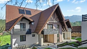 Ein modernes, zweistöckiges Haus mit geneigtem Dach, einem Balkon und einem gepflegten Rasen.