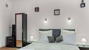 Ein Schlafzimmer mit einem Bett, Nachttischen, einem Kleiderschrank und Wandleuchten.