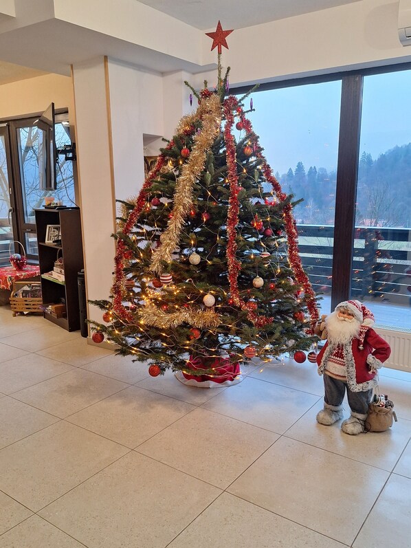 A Christmas tree with ornaments and lights, a star on top, and a Santa Claus figure beside it.