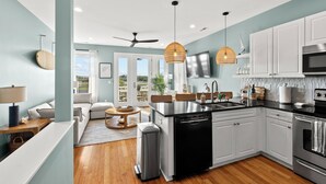 A modern kitchen with white cabinets, a black countertop, and stainless steel appliances. - Sunsets, Salty Air, and Waterfront Views (Surf City)