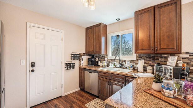 A kitchen with wooden cabinets, a granite countertop, a window, and a door.