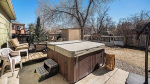 A backyard with a hot tub, outdoor furniture, and a wooden shed.