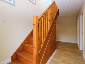 Eine Holztreppe mit Handlauf, die zu einer Zwischenebene mit einer Tür führt.