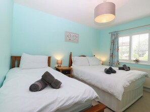 A twin room with two beds, a nightstand with a lamp, a window with curtains, and a ceiling light. - 5 Ger Afon (Pwllheli)