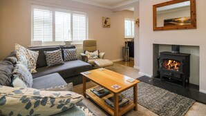 A living room with a sofa, armchairs, a coffee table, a fireplace, and a large mirror. - 5 Ger Afon (Pwllheli)