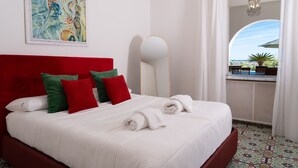 Une chambre d’hôtel avec un lit, un tableau, un miroir et une vue sur l’extérieur.