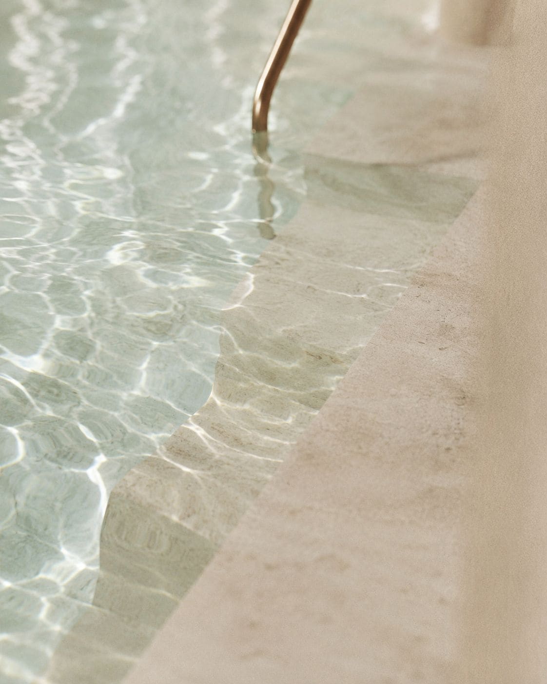 Una piscina cristalina con ondas visibles y el borde de la piscina.