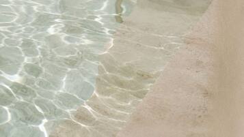 Una piscina cristalina con ondas visibles y el borde de la piscina.