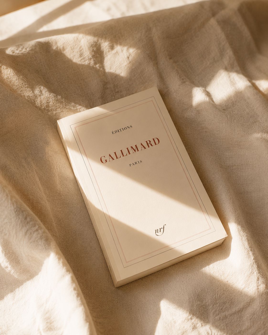 A book titled 'Éditions Gallimard Paris' on a textured fabric surface.