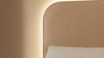 Un lit avec une tête de lit et un luminaire fixé au mur.