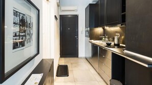 Une cuisine moderne avec des meubles de couleur sombre, une porte noire et une photo encadrée accrochée au mur.