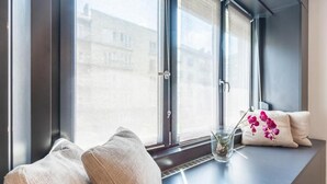 Une pièce avec une grande fenêtre, un banc et un vase rempli de fleurs.