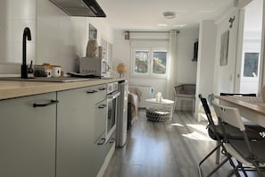 A modern kitchen with a central island, a dining area with a table and chairs, and a window providing natural light.