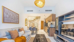 Una sala de estar moderna con sofá, mesa de centro, televisor y área de cocina.