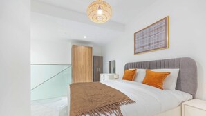 Un dormitorio moderno con cama, mesita de noche, una obra de arte en la pared y una escalera.