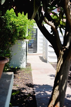 A pathway leading to a gated area with a white fence and a tree in the foreground. - A delightful section of a villa surrounded by greenery and just a stone's throw from the sea (Quartu Sant'Elena)