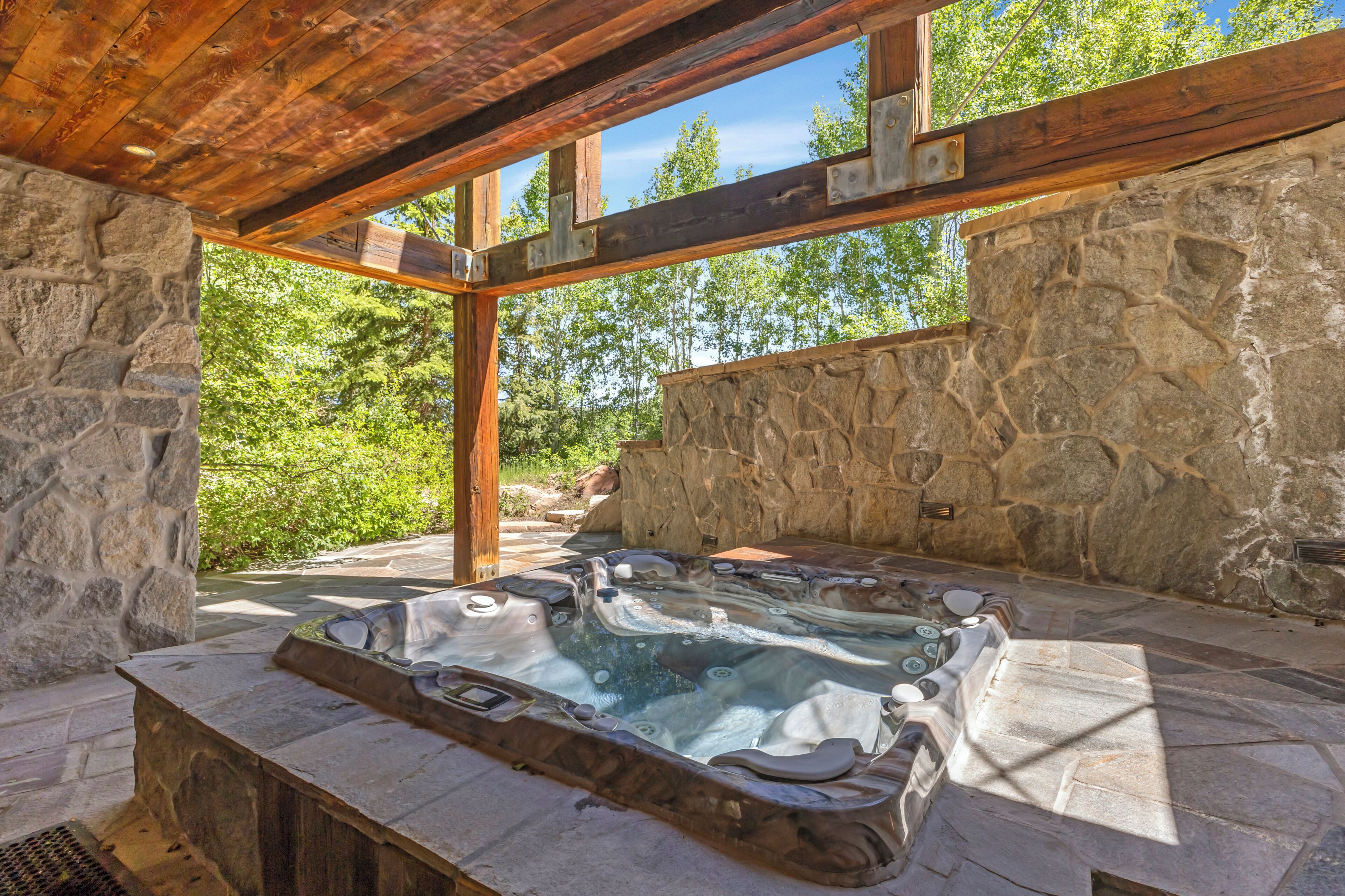 Un espace dédié à un bain à remous, avec des murs en pierre, un plafond en bois et des murs en pierre.