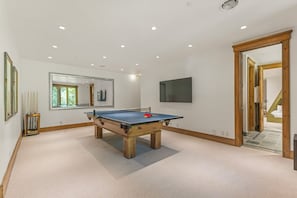 Ein Zimmer mit Kicker, großem Spiegel und Fernseher an der Wand.