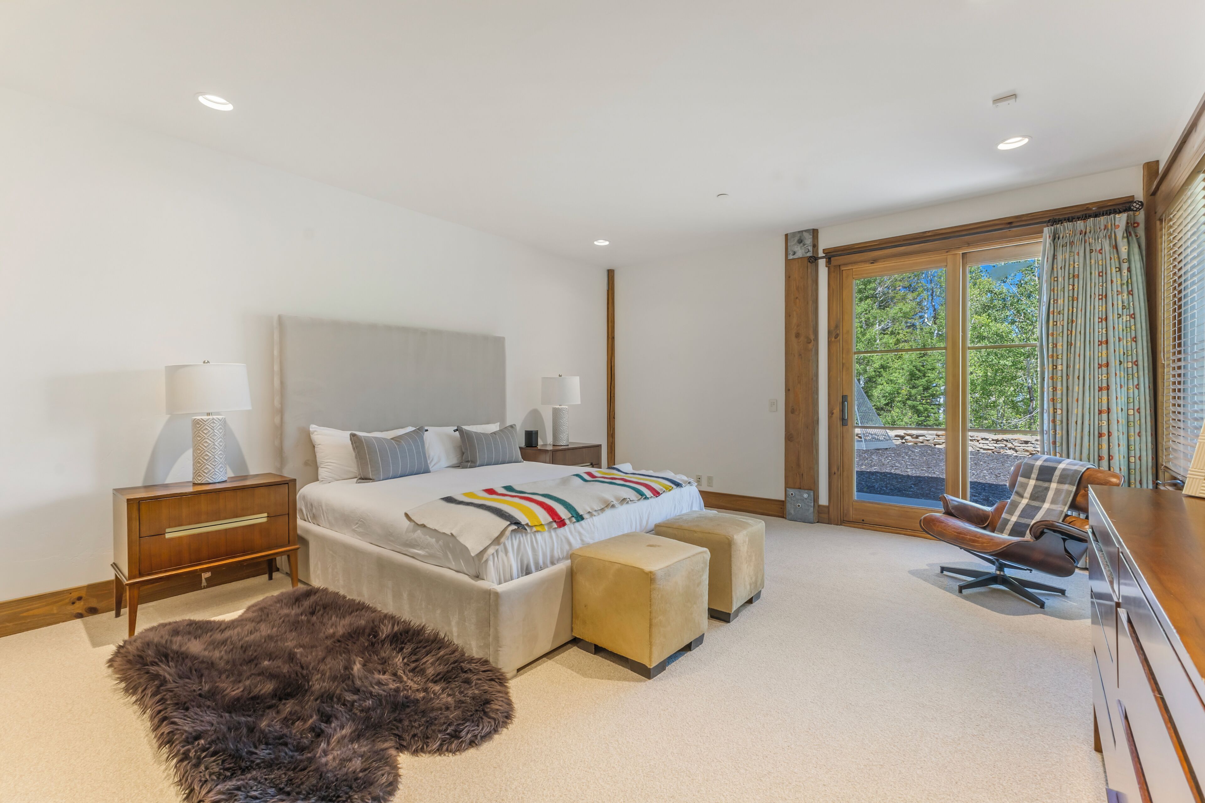 Un dormitorio moderno con una cama grande, un escritorio, una silla y vistas al exterior a través de una ventana.