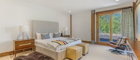 Un dormitorio moderno con una cama grande, un escritorio, una silla y vistas al exterior a través de una ventana.