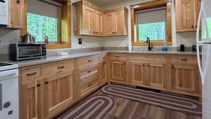 Una cocina con armarios de madera, horno empotrado, microondas y un lavabo.