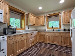 Eine Küche mit Holzschränken, einem Backofen, einer Mikrowelle und einem Spülbecken.