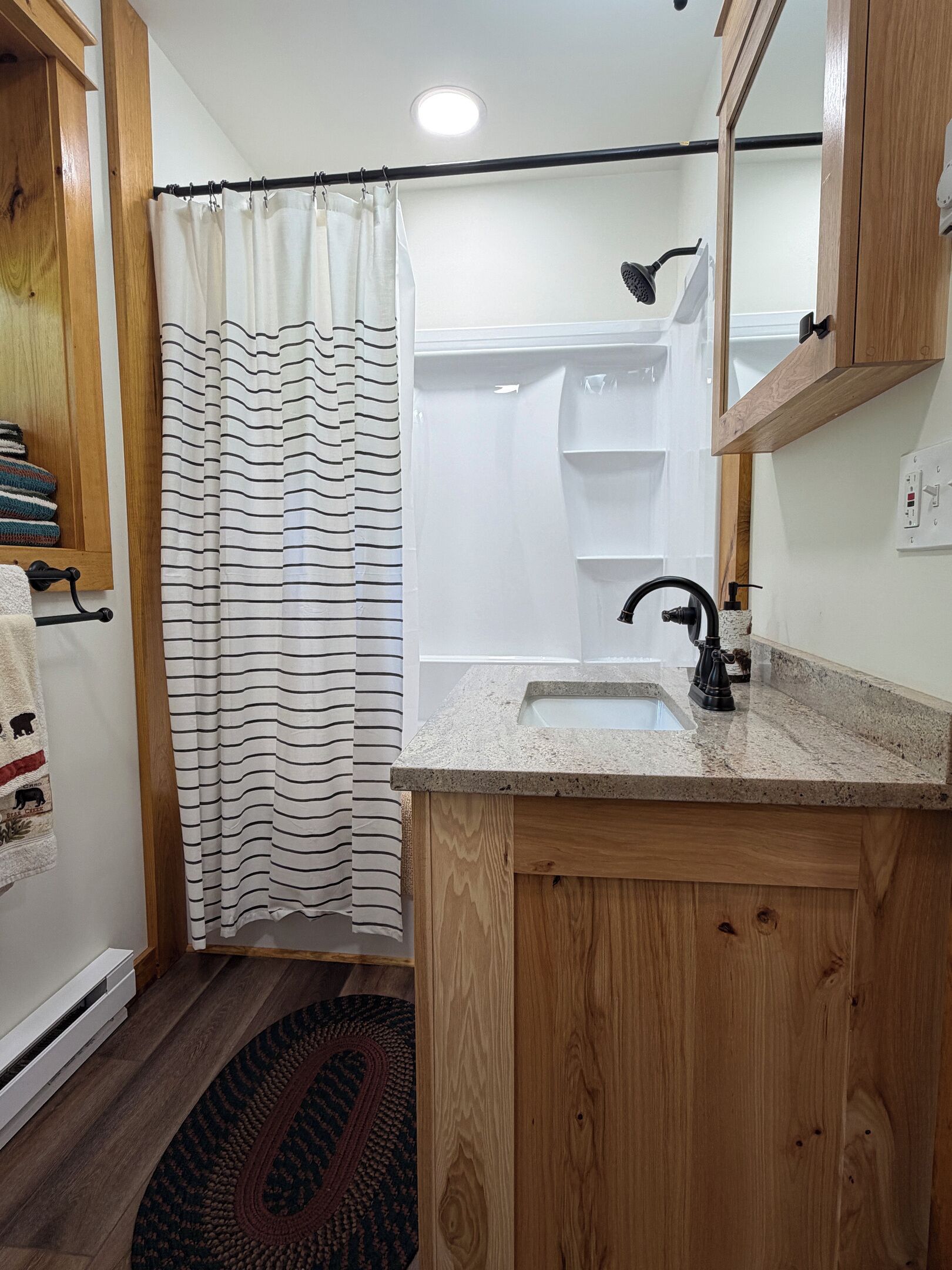 A bathroom with a shower, a sink, wooden cabinets, and a mirror.